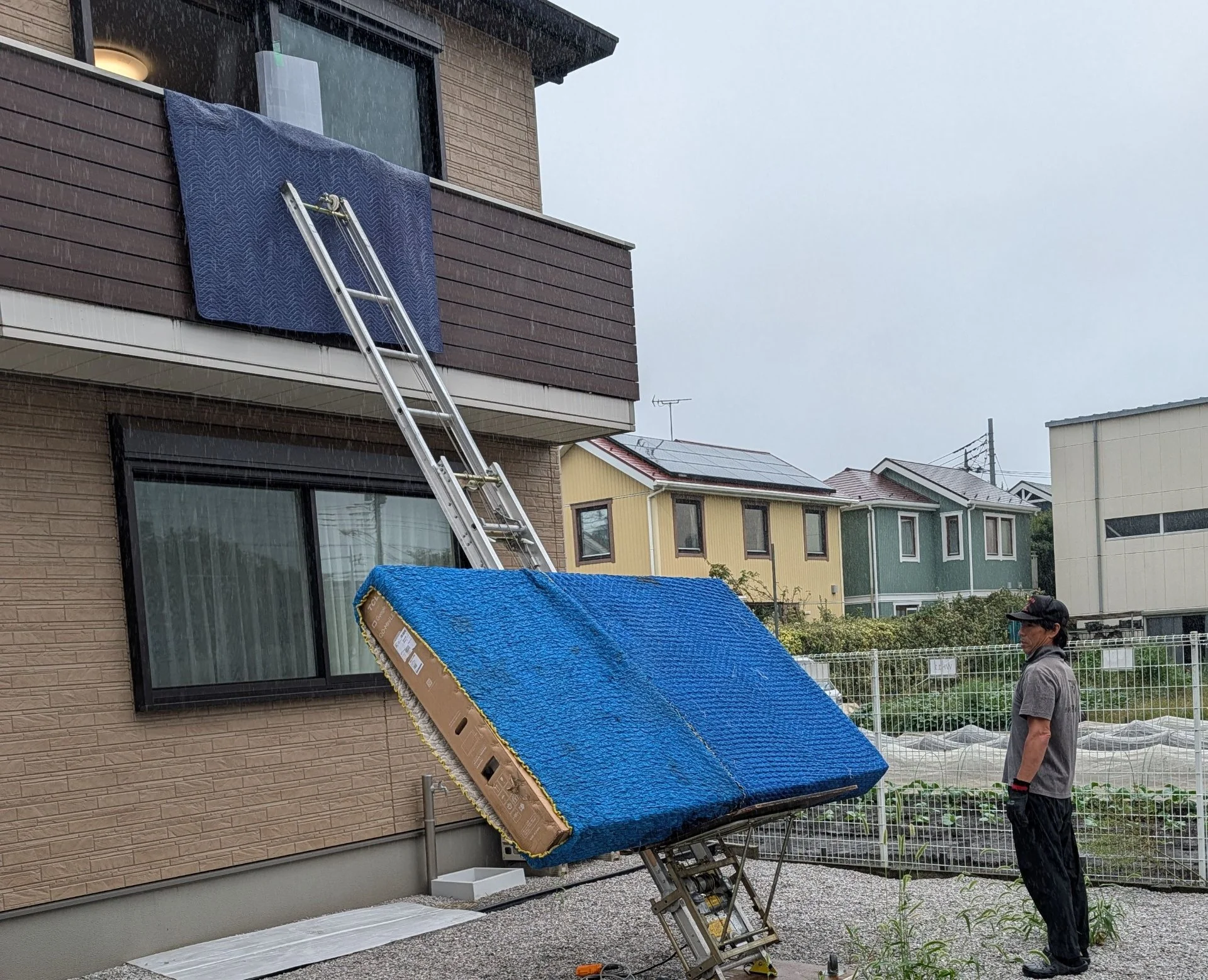 電動はしごとリフトを使い、建物二階の窓から荷物を搬入する作業員たち