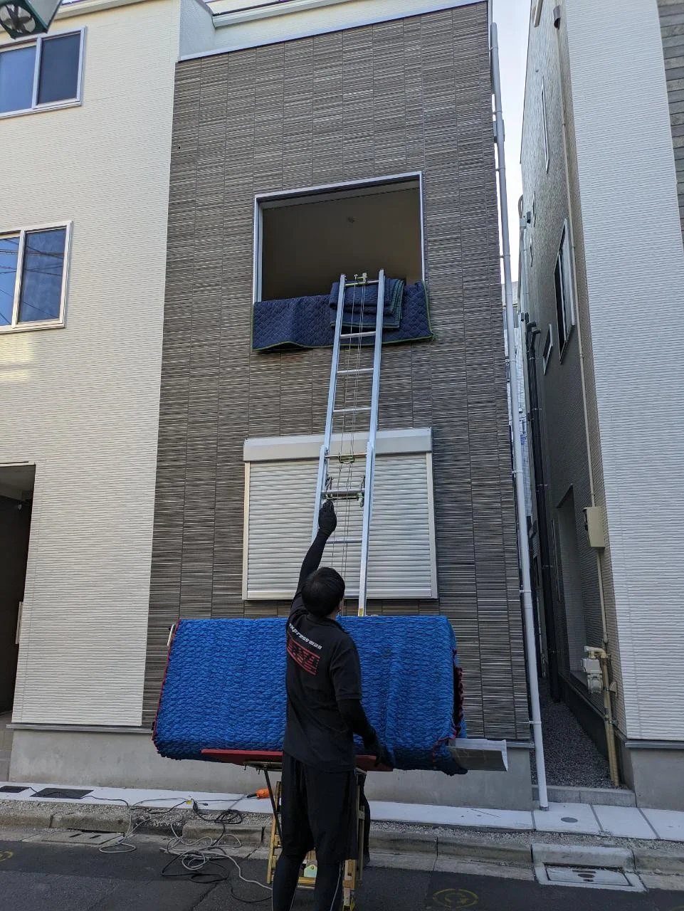 台車に積んだ引越し荷物を建物の通路で搬送する作業